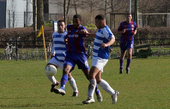 Gio Leeflang tussen twee Blauw Wit spelers